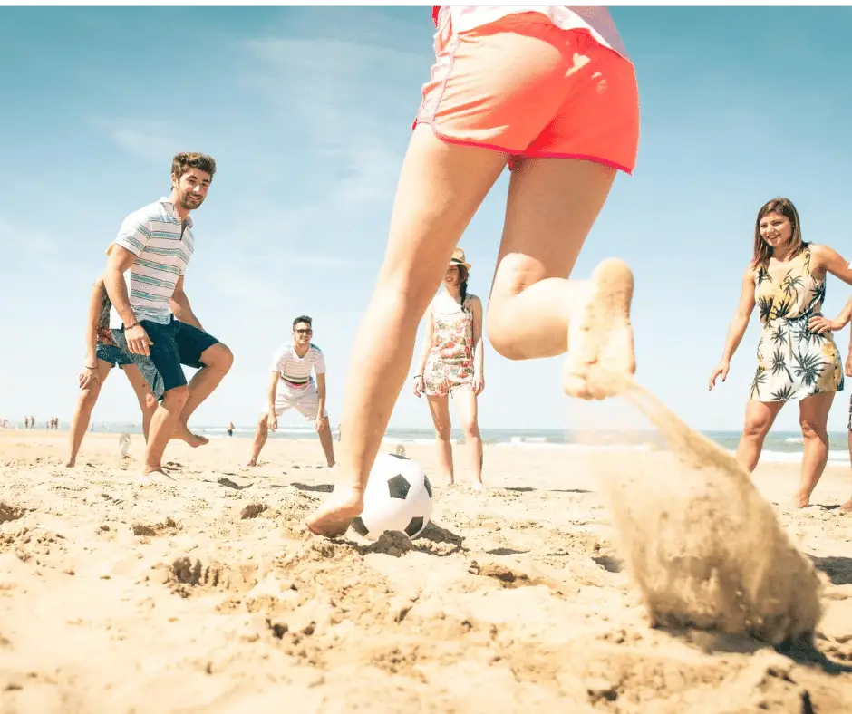 friends playing soccer on the beach